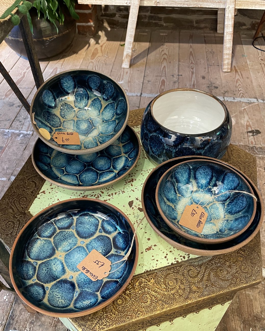 Deep blue bowls with a floral break-up glaze, each with a handwritten Ellie Bells price tag