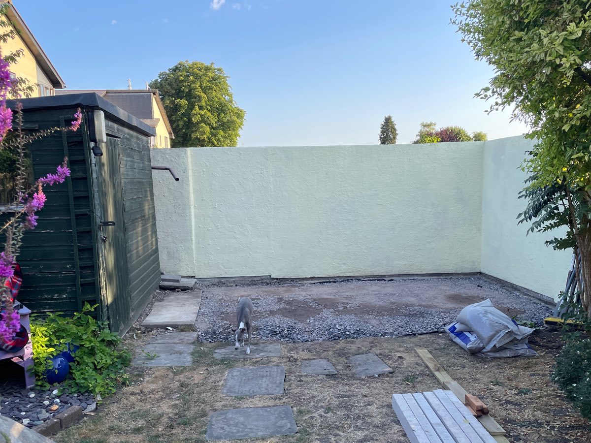 A cleared, levelled patch of ground in front of a pale rendered wall