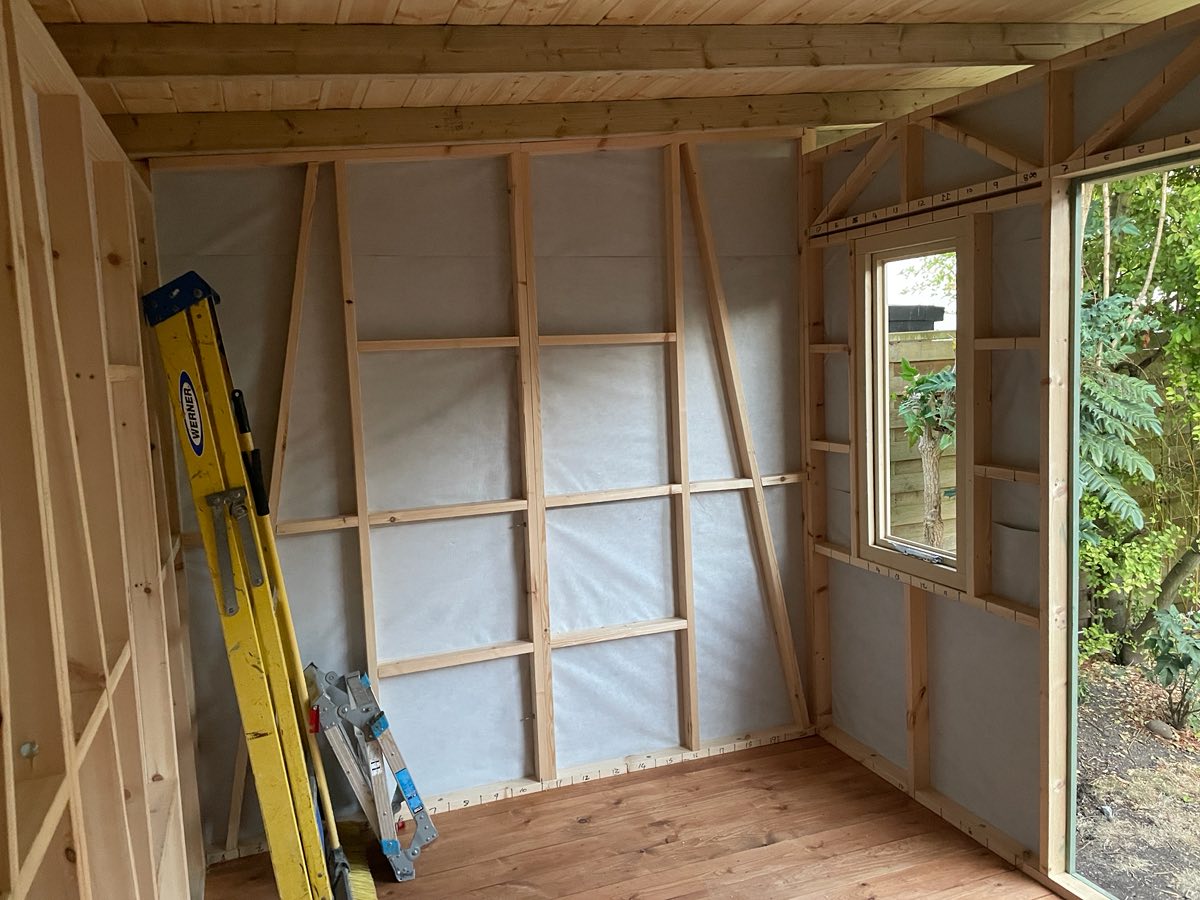 Inside the studio: timber stud framing over a white membrane, with a window