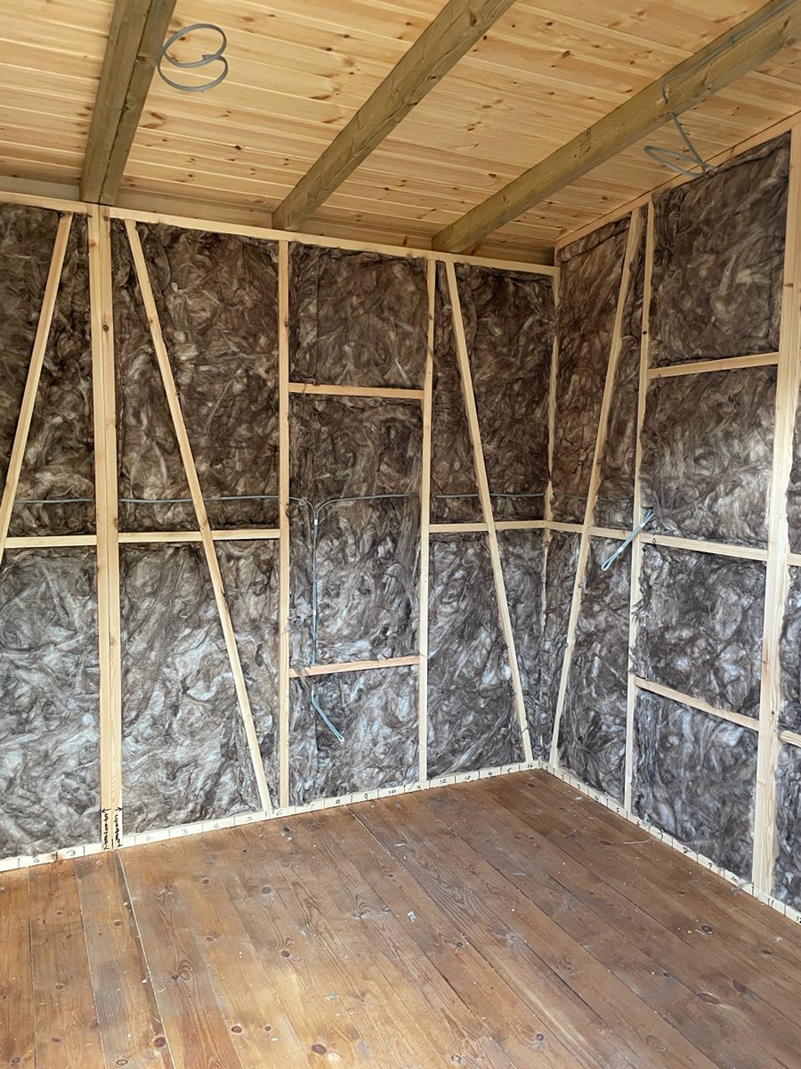 Insulation packed between the wall studs, with a pine ceiling above