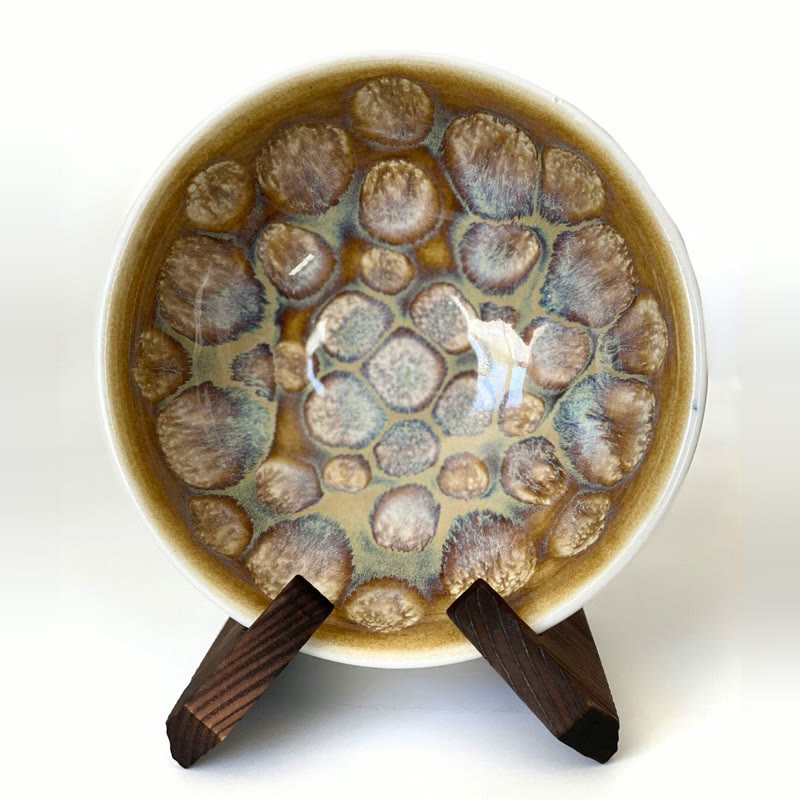 Bowl on a wooden stand with an amber glaze broken into soft lilac blooms