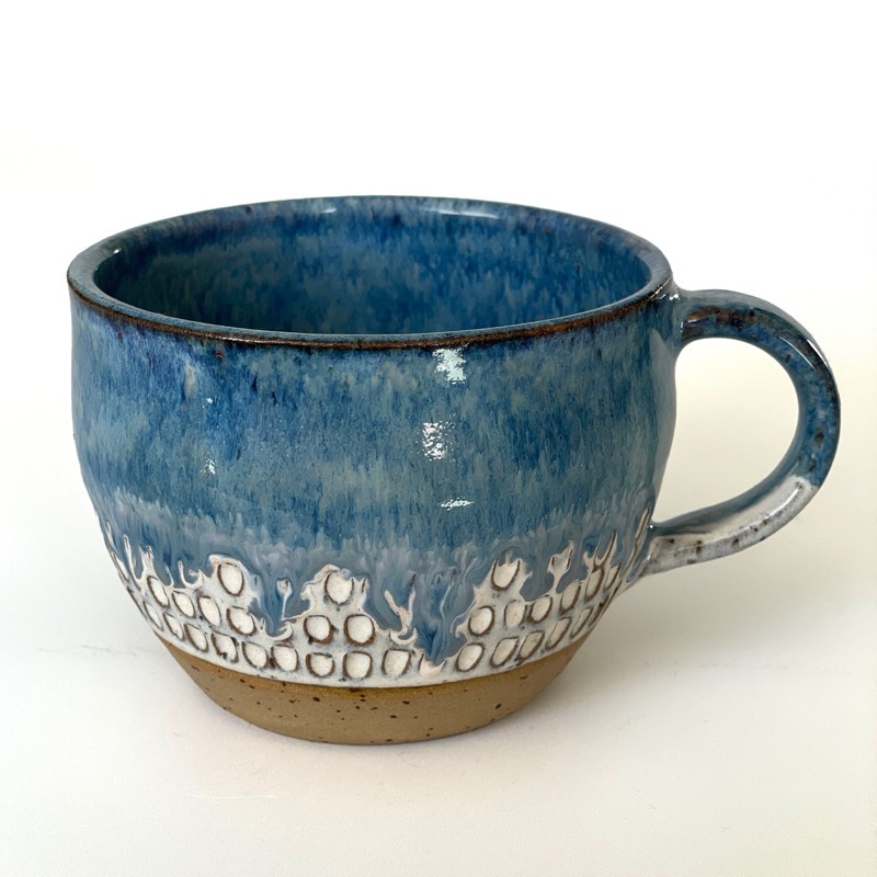 Round cappuccino cup in blue glaze dripping over carved white dots