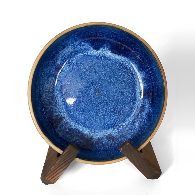 Cobalt blue bowl on a stand with a pale blue glaze pooling in the centre