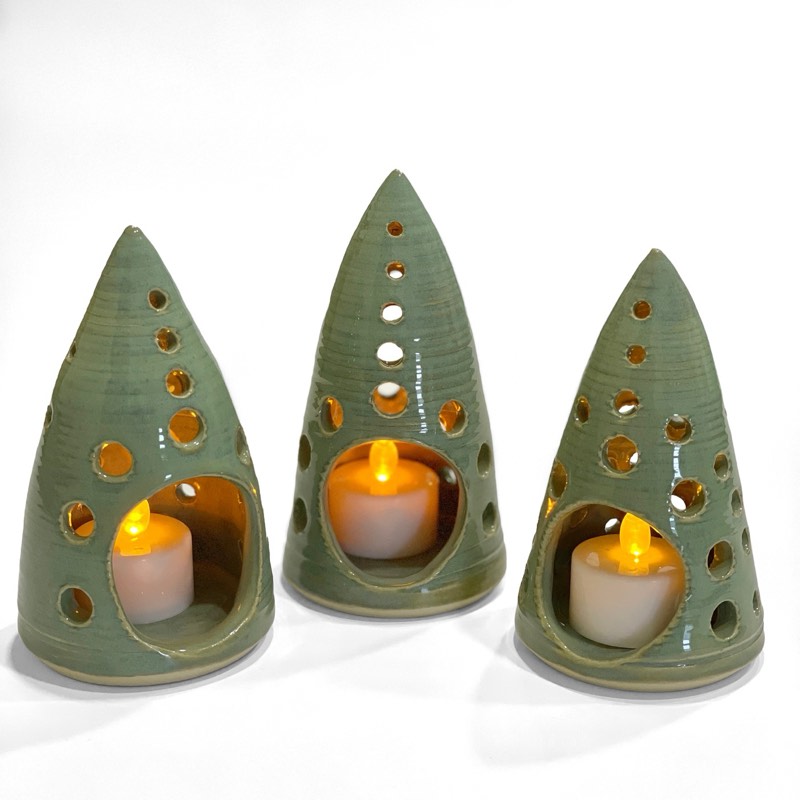 Three sage green pointed tealight luminaries glowing