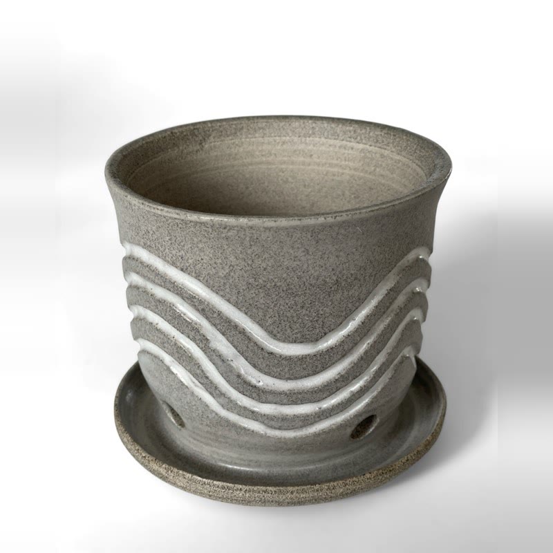 Grey speckled planter with white wave lines on a saucer