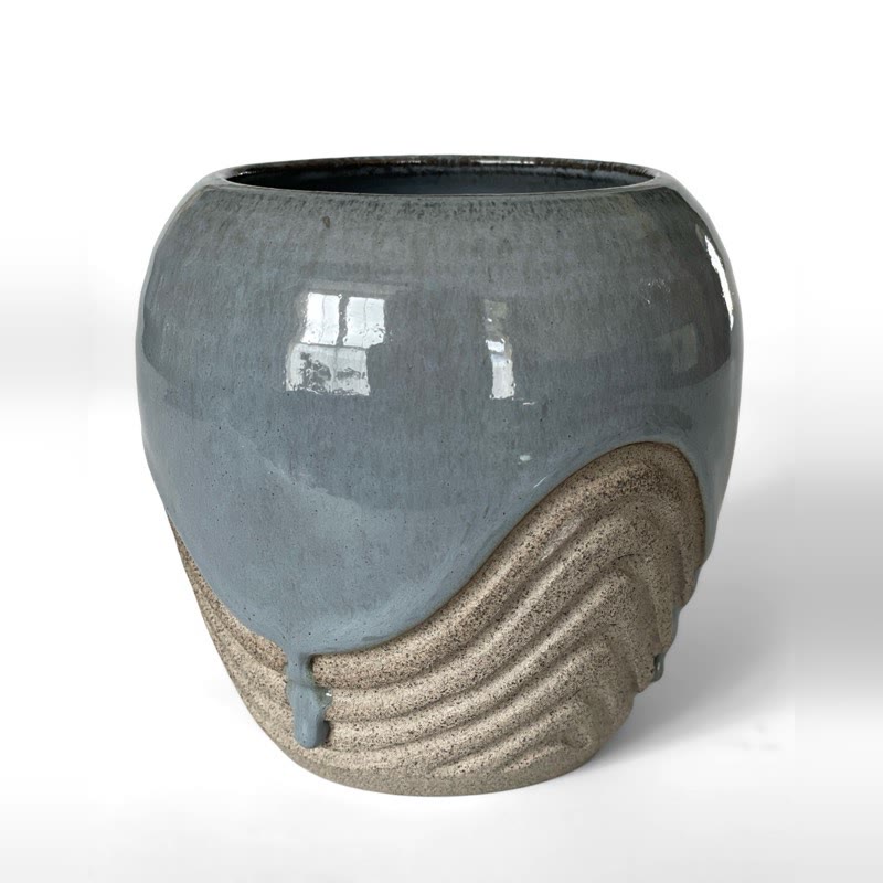 Glossy grey-blue vase with textured bare-clay waves at the base