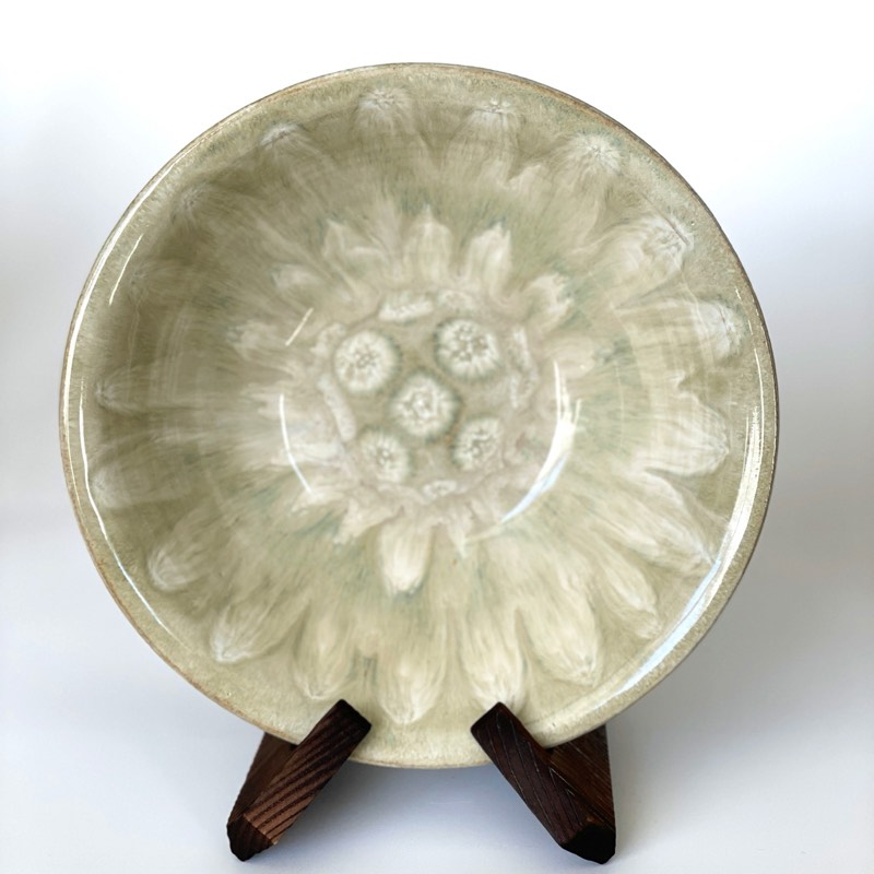 Pale sage bowl on a stand with a white flower-like crystal pattern