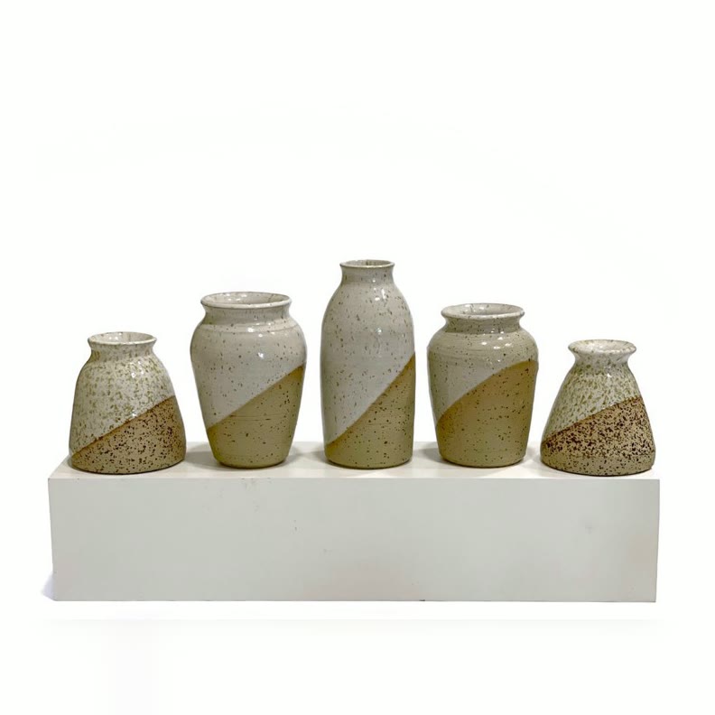 Five small speckled bud vases in a row