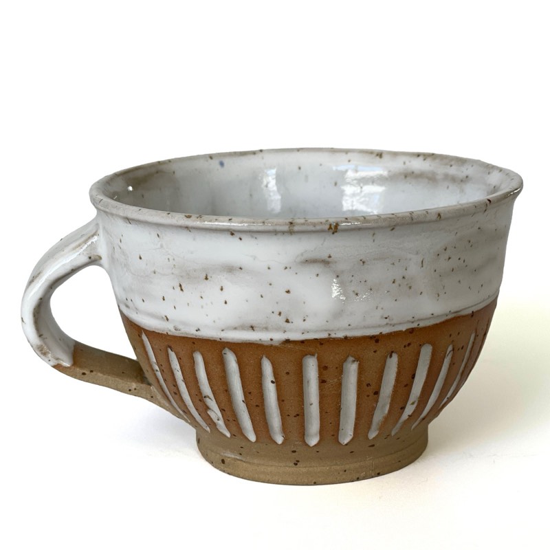 White glazed cappuccino cup over a speckled clay base carved with vertical lines