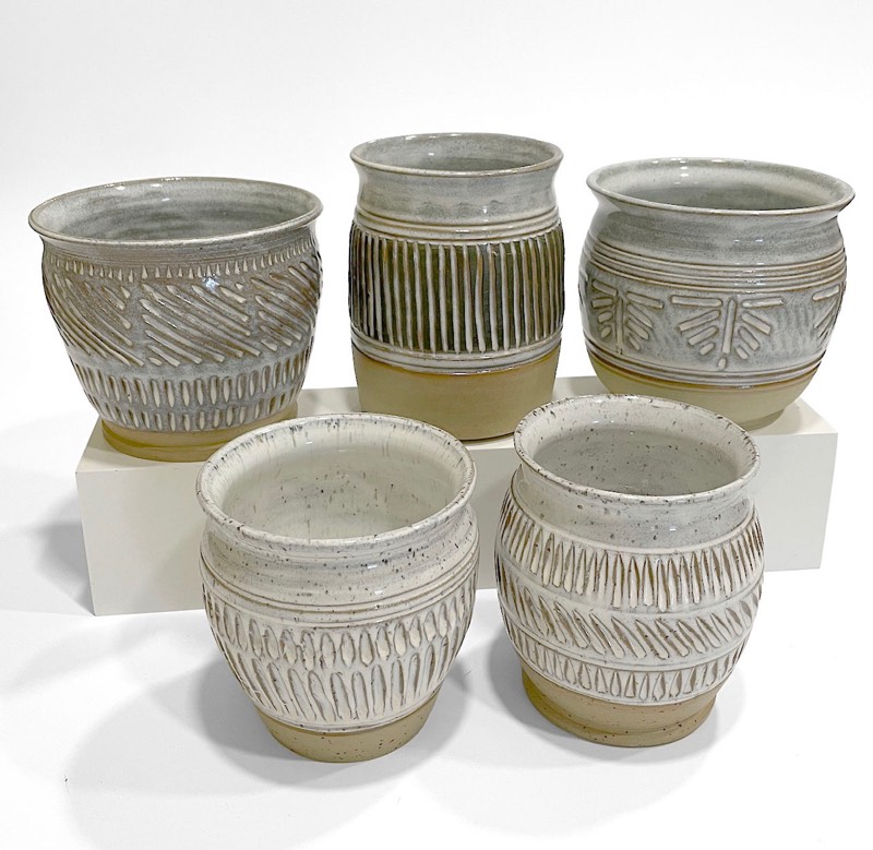 Five carved speckled white pots grouped together