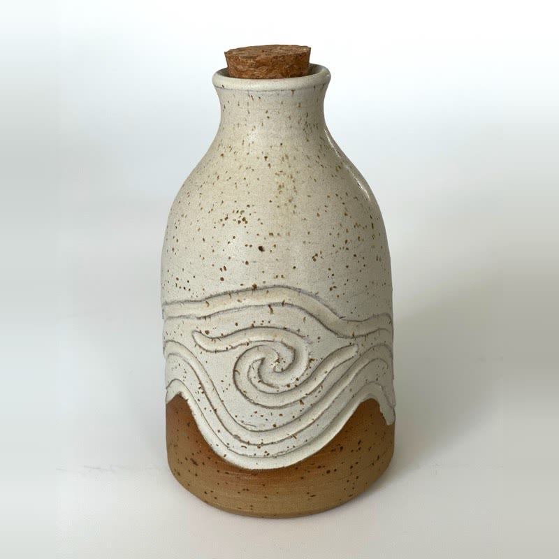 Speckled white bottle with a carved swirl and a cork stopper