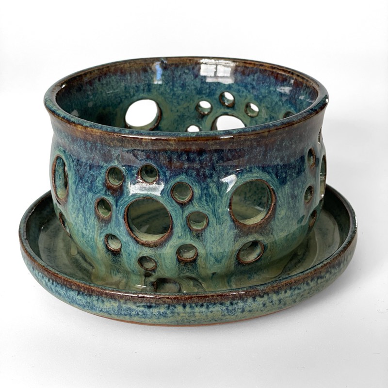Teal planter with pierced holes on a matching saucer