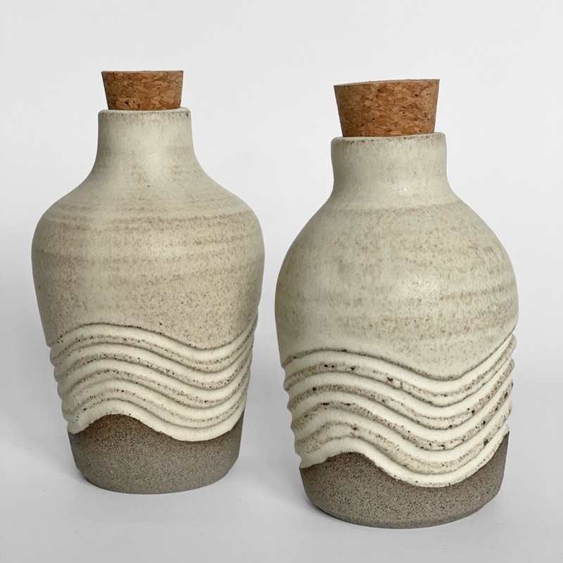 Two speckled bottles with carved white waves and cork stoppers