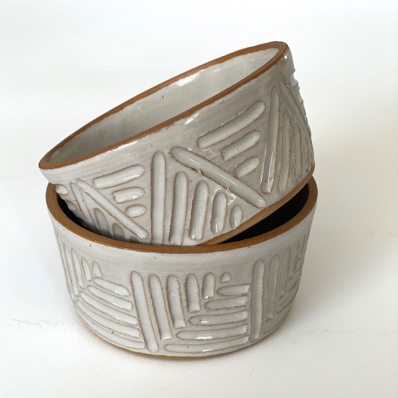 Two white bowls carved with crossing lines, nested together